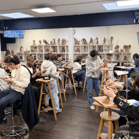 Atelier de sculpture détudiants avec argile, armatures et sculptures exposées.