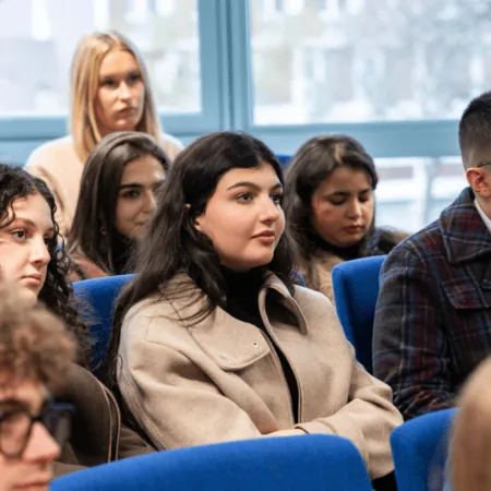 Audience jeune attentive en conférence, chaises bleues, séminaire et présentation.