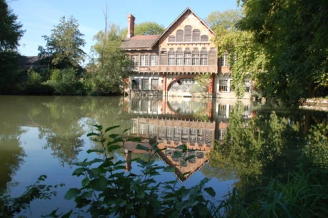 Maison ancienne en brique au bord dun étang, reflet parfait.