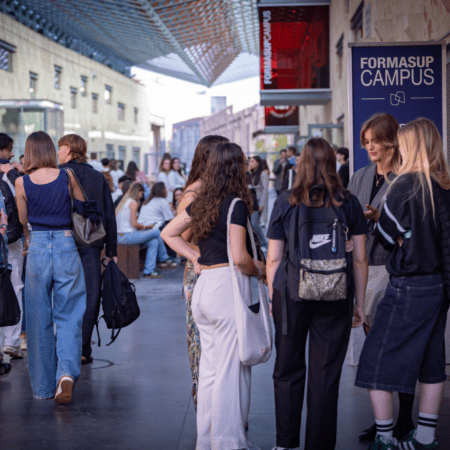 Passage couvert du campus, terrasse ombragée avec étudiants et sacs à dos.
