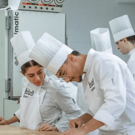 Chefs pâtissiers en atelier façonnant pâte feuilletée sur table farinée.