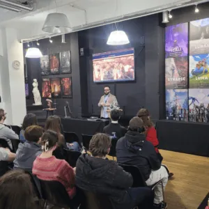 Conférence art urbain en galerie avec intervenant, écran, affiches colorées et public attentif.