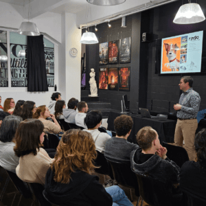 Conférence en studio créatif : atelier design, présentation écran et public attentif.