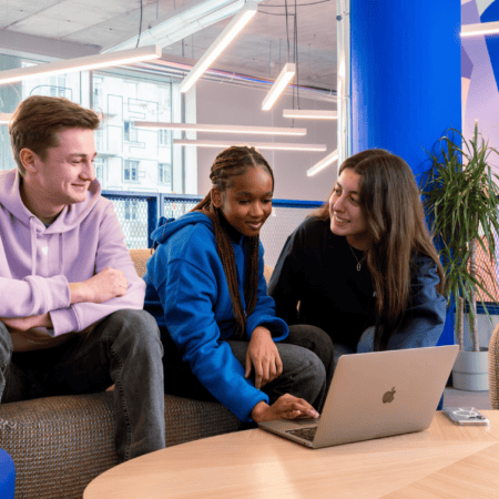 Espace coworking lounge moderne : trois jeunes collaborent autour dun ordinateur portable.