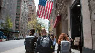 Drapeau américain au-dessus de piétons avec sacs à dos dans une rue de centre-ville.
