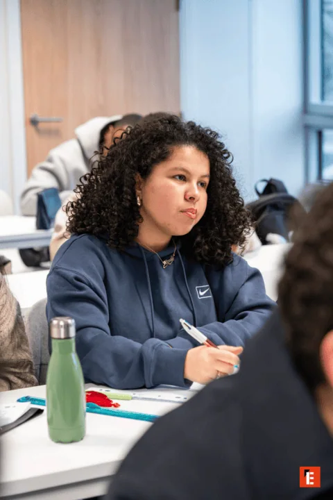 Élève concentré en classe prenant des notes pendant un cours.