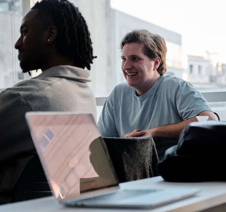 Réunion déquipe conviviale en espace de coworking lumineux avec ordinateur portable.