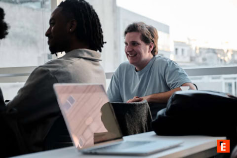 Réunion déquipe conviviale en espace de coworking lumineux avec ordinateur portable.