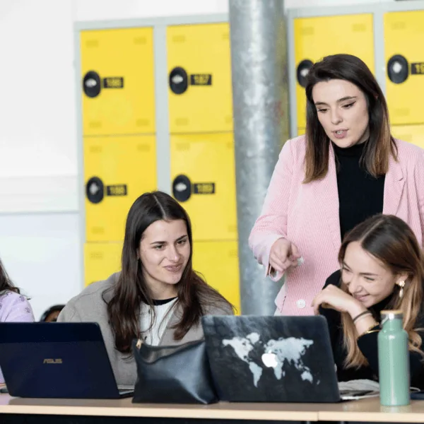 Étudiantes en travail déquipe autour dordinateurs portables devant casiers jaunes.