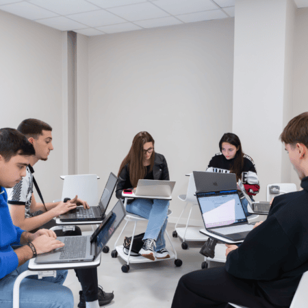 Étudiants en salle détude, travaillant sur ordinateurs portables en groupe silencieux.