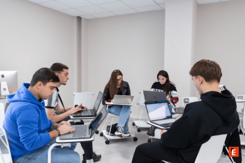 Étudiants en salle détude, travaillant sur ordinateurs portables en groupe silencieux.