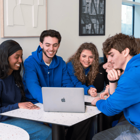 Étudiants en groupe autour dun ordinateur portable, session de travail collaboratif moderne.