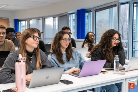 Étudiants en salle de cours utilisant ordinateurs portables lors dune formation universitaire moderne.