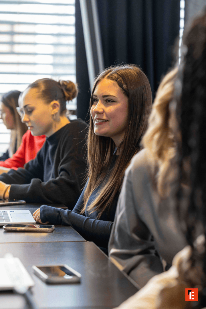 Femme souriante à lordinateur en réunion de bureau collaborative, étudiants concentrés.