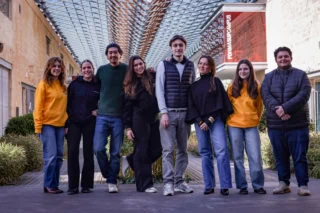 Portrait de groupe détudiants sur campus sous arcade vitrée moderne.