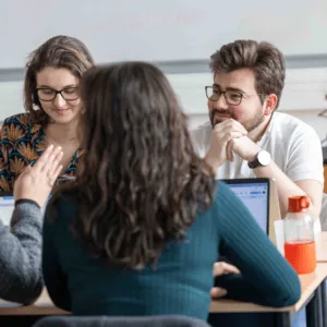 Groupe détude collaboratif autour dune table avec ordinateurs en salle de réunion.