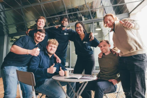 Photo déquipe de collègues souriants en espace de travail moderne, ambiance conviviale au café.
