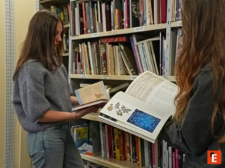 Deux lecteurs feuilletant des livres dans une bibliothèque aux rayonnages remplis.
