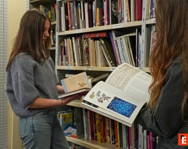 Deux lecteurs feuilletant des livres dans une bibliothèque aux rayonnages remplis.