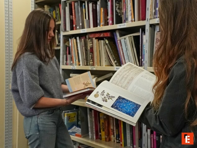 Deux lecteurs feuilletant des livres dans une bibliothèque aux rayonnages remplis.