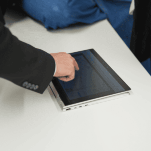 Tablette tactile convertible, main interagissant avec écran dordinateur professionnel sur bureau blanc.