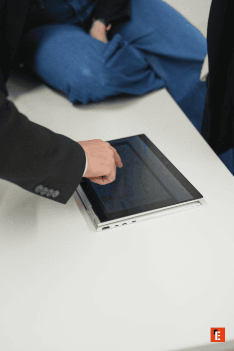 Tablette tactile convertible, main interagissant avec écran dordinateur professionnel sur bureau blanc.