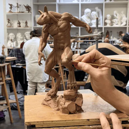 Maquette en argile dun être lapin humanoïde dans un atelier de sculpture, mains dartiste.