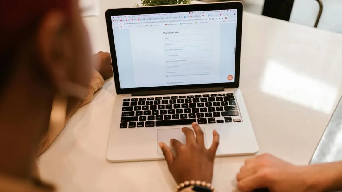 Ordinateur portable avec formulaire en ligne, mains saisissant des données lors dune consultation.