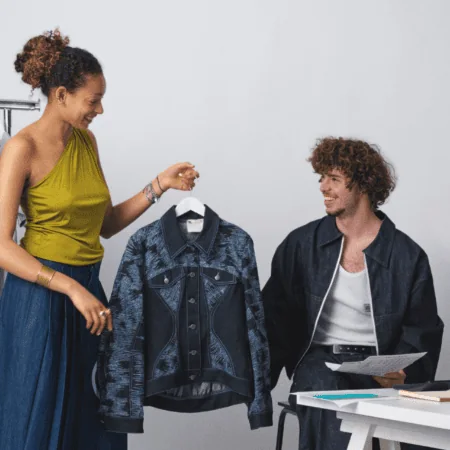 Présentation veste en jean en studio par stylistes, discussion collaborative autour du vêtement.