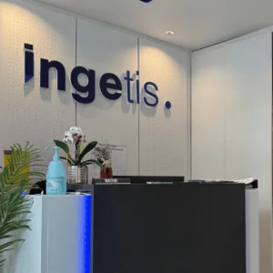 Réception moderne Ingetis avec logo bleu, comptoir minimaliste, éclairage LED et orchidée.