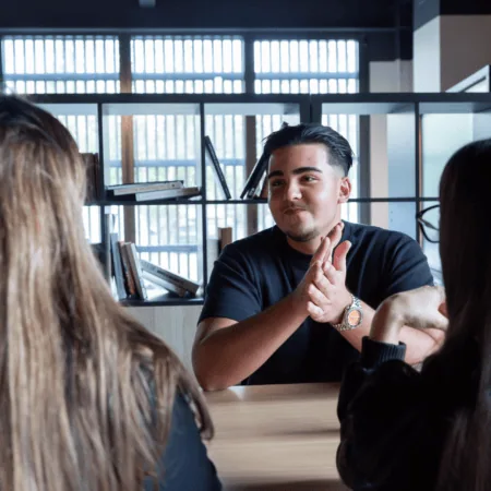Réunion informelle : homme discutant avec collègues autour dune table de bureau moderne.
