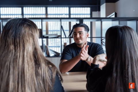 Réunion informelle : homme discutant avec collègues autour dune table de bureau moderne.