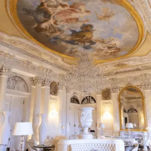 Salle à manger de luxe avec plafond peint rococo, lustre en cristal et mobilier contemporain.
