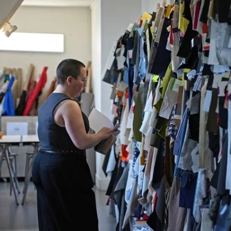 Atelier textile, personne examinant un mur déchantillons de tissus multicolores.