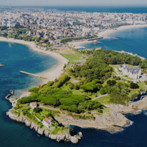 Vue aérienne dune pointe rocheuse, plages, falaises et château côtier.
