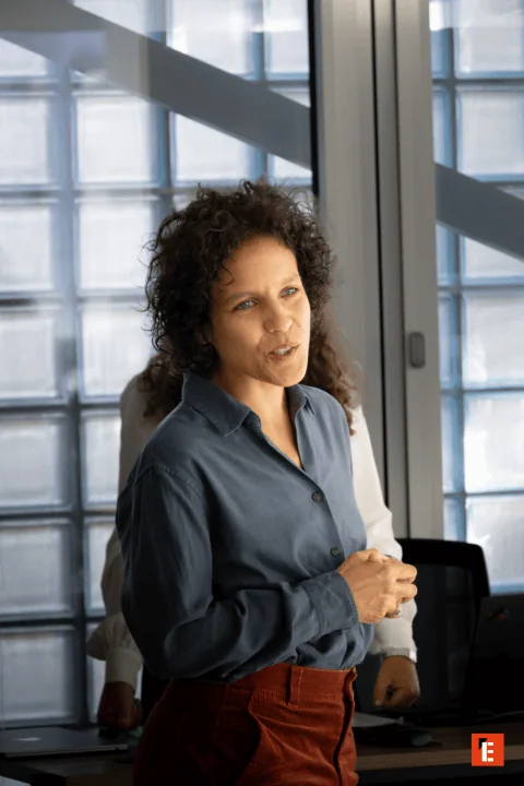 Deux hommes en réunion avec ordinateurs Apple dans espace de travail moderne près dascenseurs.