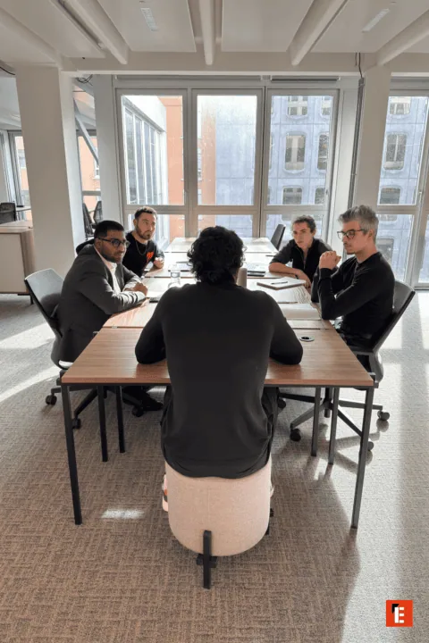 Collègues en coworking sur canapé jaune, bureau moderne, ordinateurs portables et collaboration.
