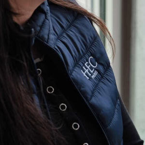 Étudiants HEC Paris en sweat à capuche discutant sur gradins damphithéâtre avec coussins colorés.