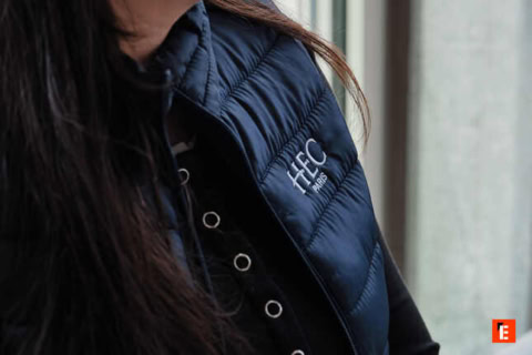 Étudiants HEC Paris en sweat à capuche discutant sur gradins damphithéâtre avec coussins colorés.