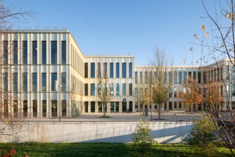 Canal tranquille avec reflets, mur en pierre, maison blanche et arbres au soleil.