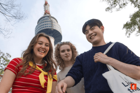 Trois jeunes amis souriants devant une tour dobservation urbaine, journée en plein air.