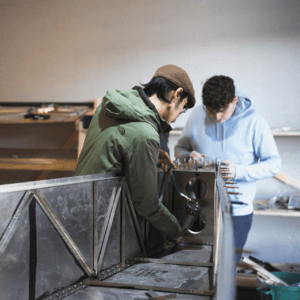 Atelier dassemblage métallique, rivetage manuel avec outil pneumatique par deux ouvriers concentrés.