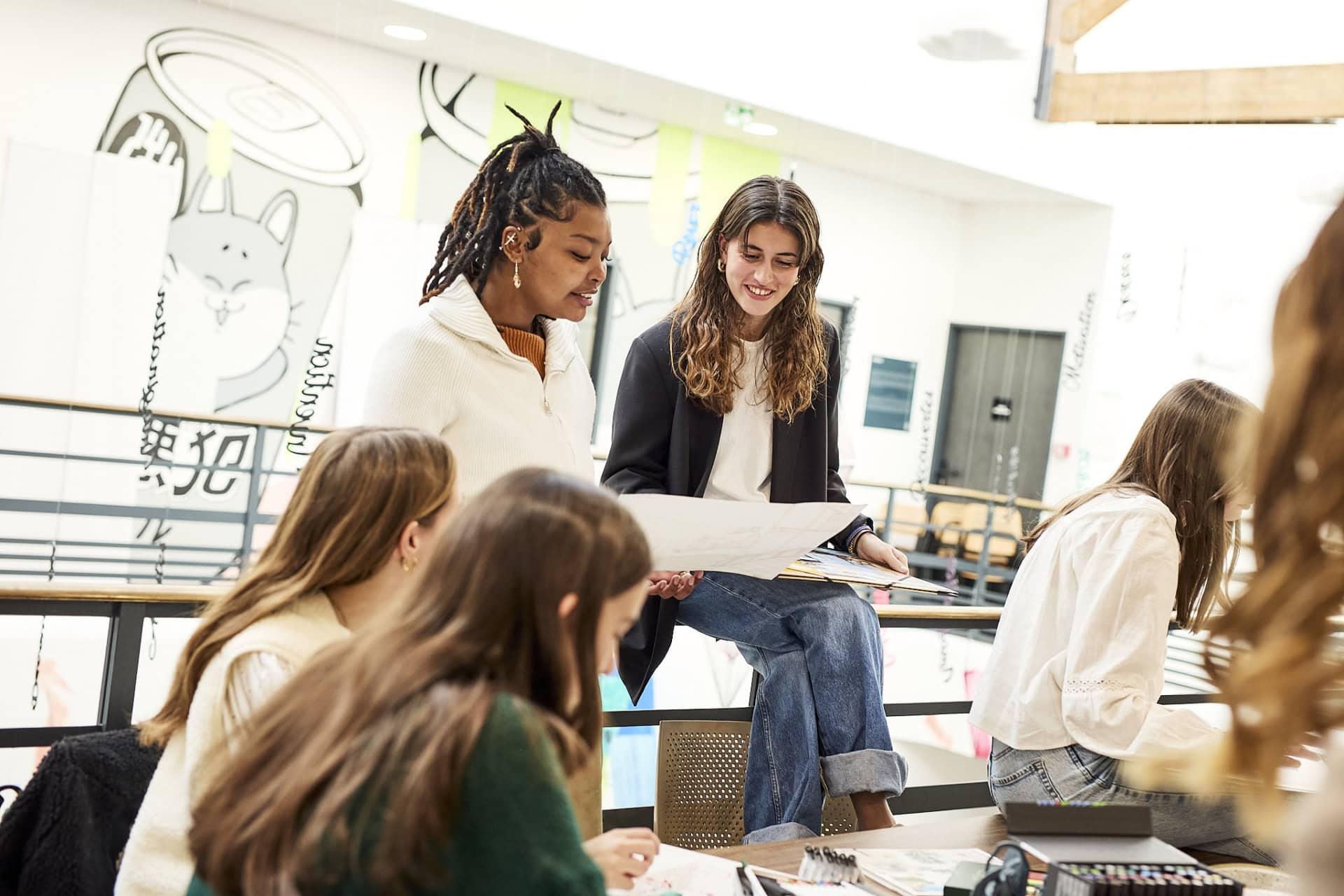 Étudiants en atelier créatif collaboratif, dessin et brainstorming près dune fresque murale lumineuse.
