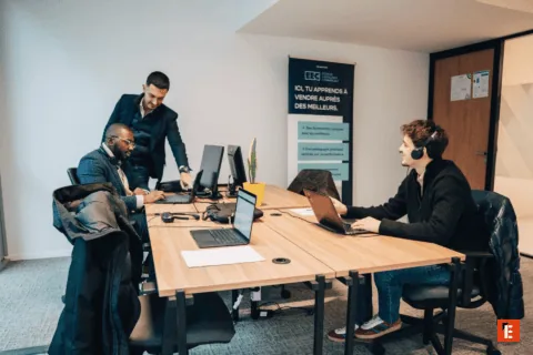 Équipe en bureau collaboratif autour dordinateurs pour formation vente et réunion.