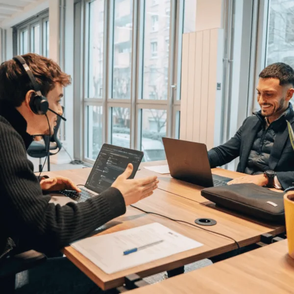Bureau coworking lumineux avec collègues en collaboration, ordinateurs et grandes fenêtres.