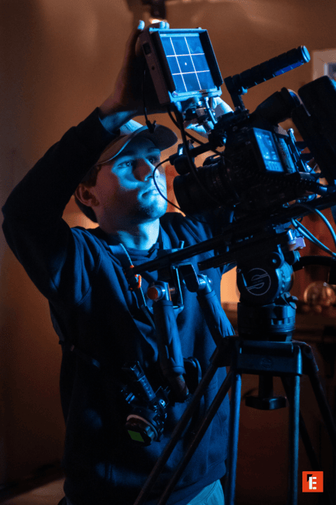 Opérateur caméra cinéma réglant moniteur externe sur plateau, équipement vidéo professionnel.