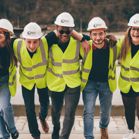 Cinq personnes en gilets fluo et casques ESCT, équipe souriante au bord de leau.