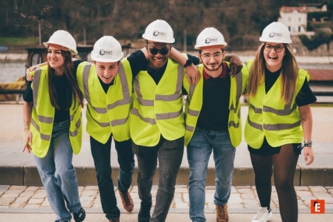 Cinq personnes en gilets fluo et casques ESCT, équipe souriante au bord de leau.