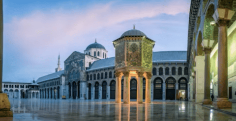 Cour au pavillon octogonal illuminé, reflets sur marbre, arcades et minaret au crépuscule.