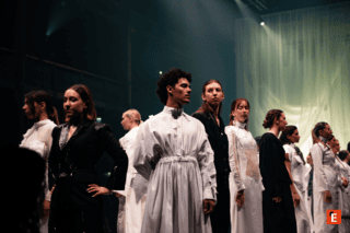 Défilé de mode minimaliste en noir et blanc, mannequins alignés sous projecteur.